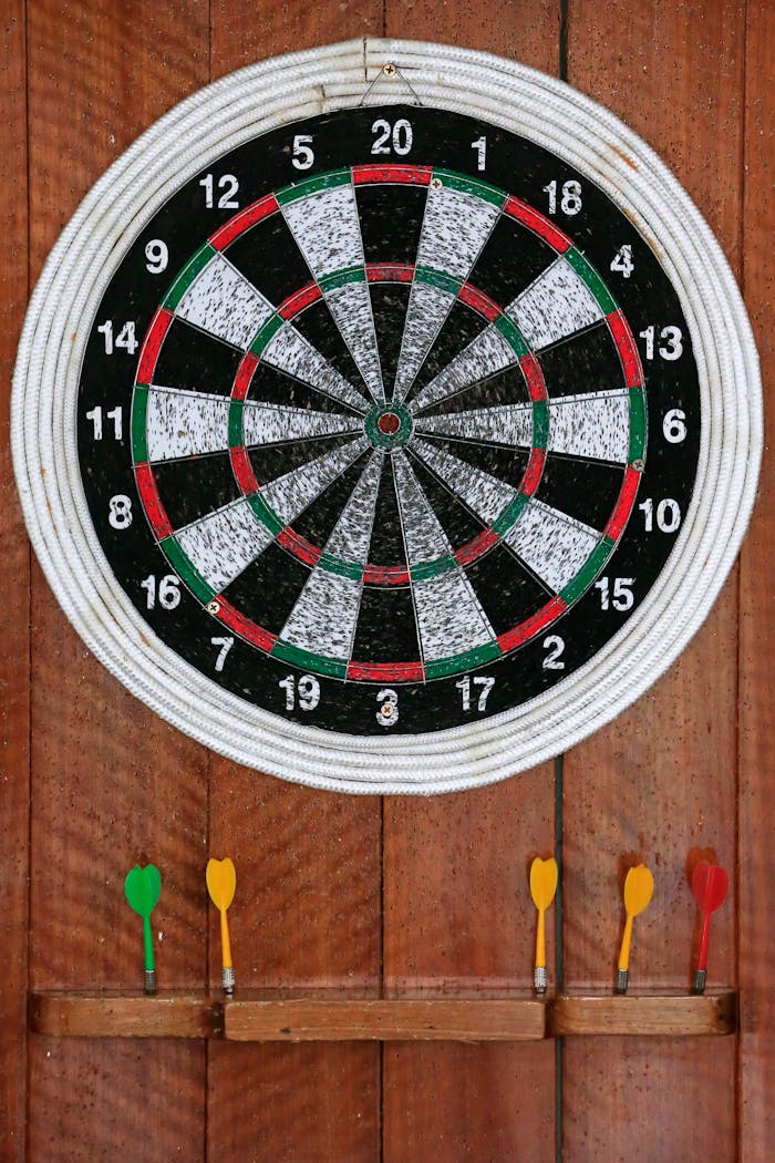 Close-up of a dartboard with colorful darts on a wooden background, ideal for sports themes.